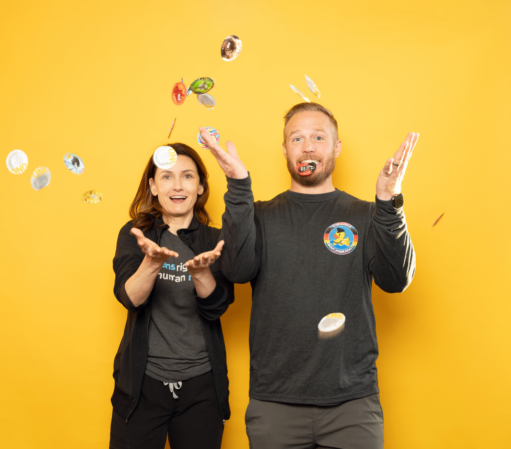 Two staff members from Central Outreach Wellness Center throwing round condoms into the air