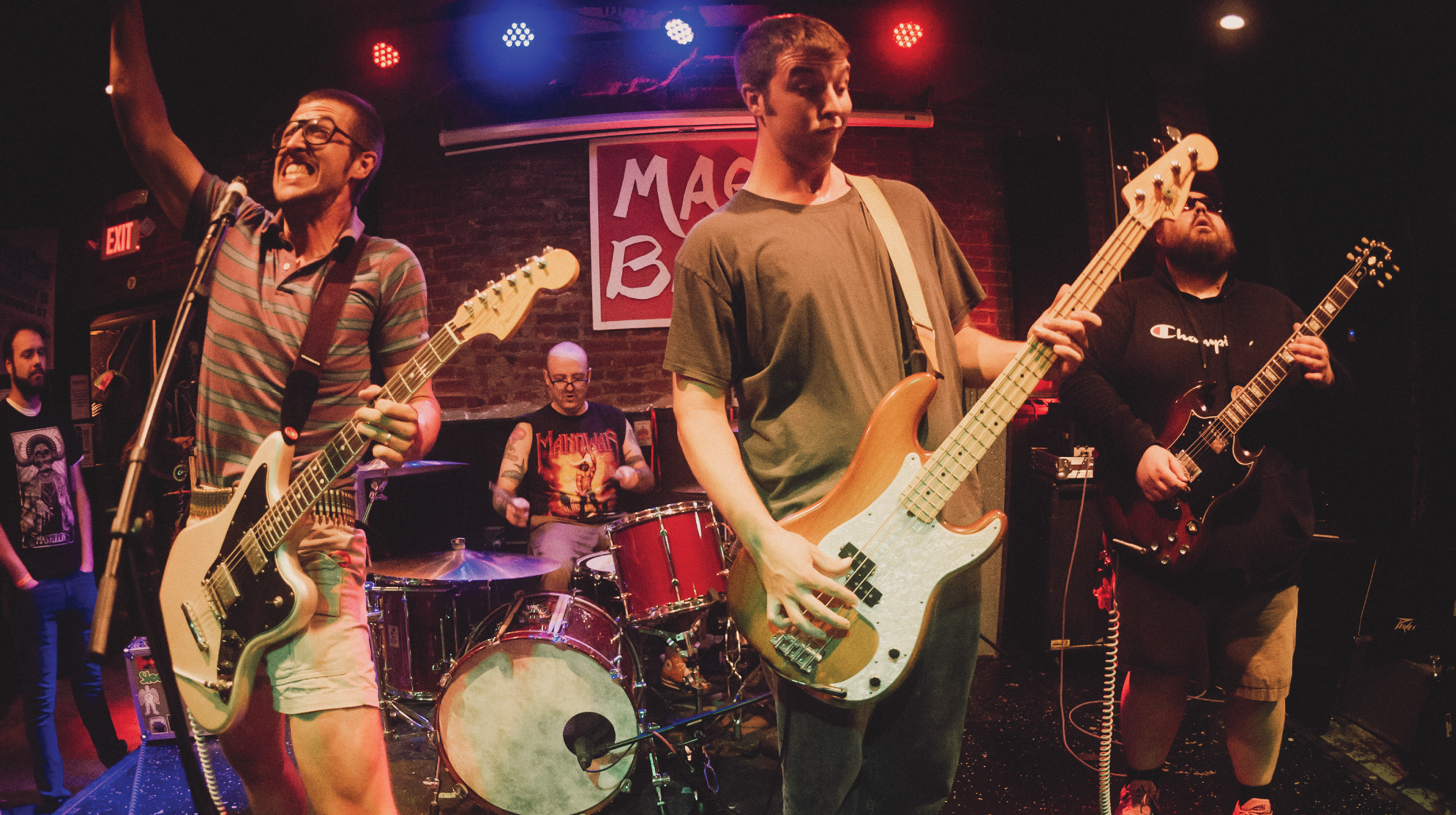 The band Faerie Ring performs on stage surrounded by blue, pink, and purple stage lights.